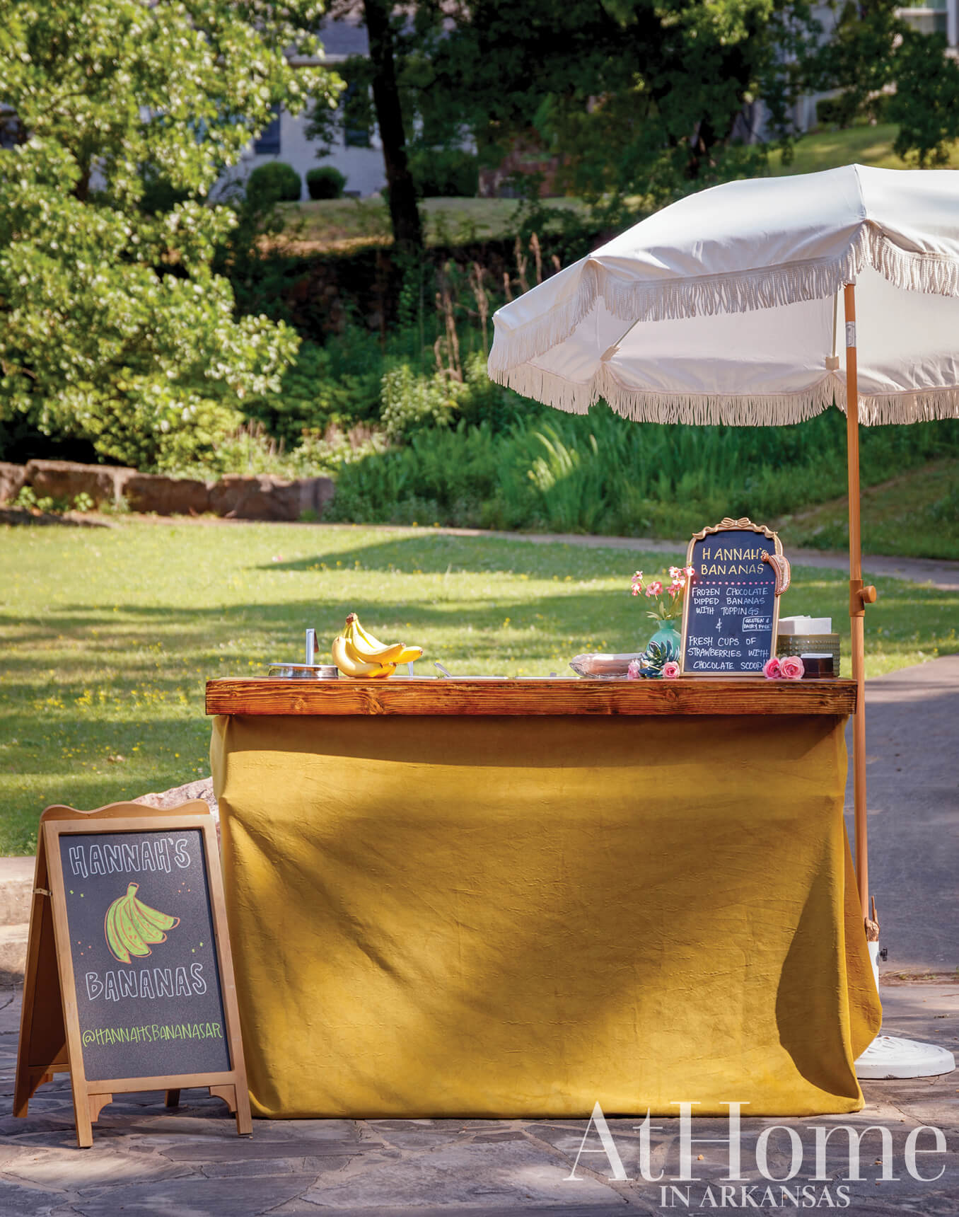 Yellow wooden fruit stand with signage and fresh bananas.