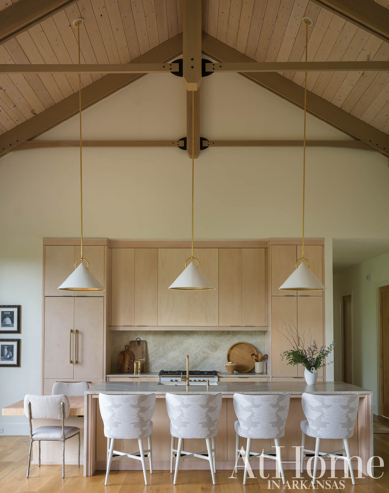 Light wood kitchen with island, pendant lights, and upholstered chairs.