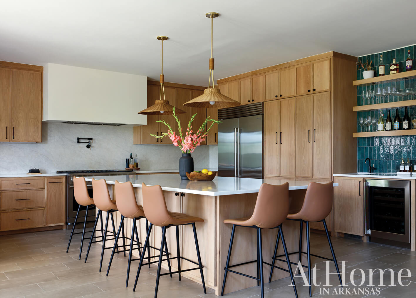 Wooden kitchen cabinets, island, and bar stools with teal tile backsplash.