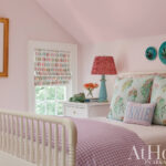 Pink bedroom with white bed, patterned drapes, and turquoise accents.