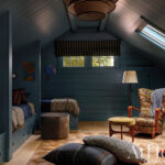 Blue-painted attic bedroom with two beds and a chair.
