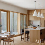 Wooden kitchen with pendant lights and marble island.