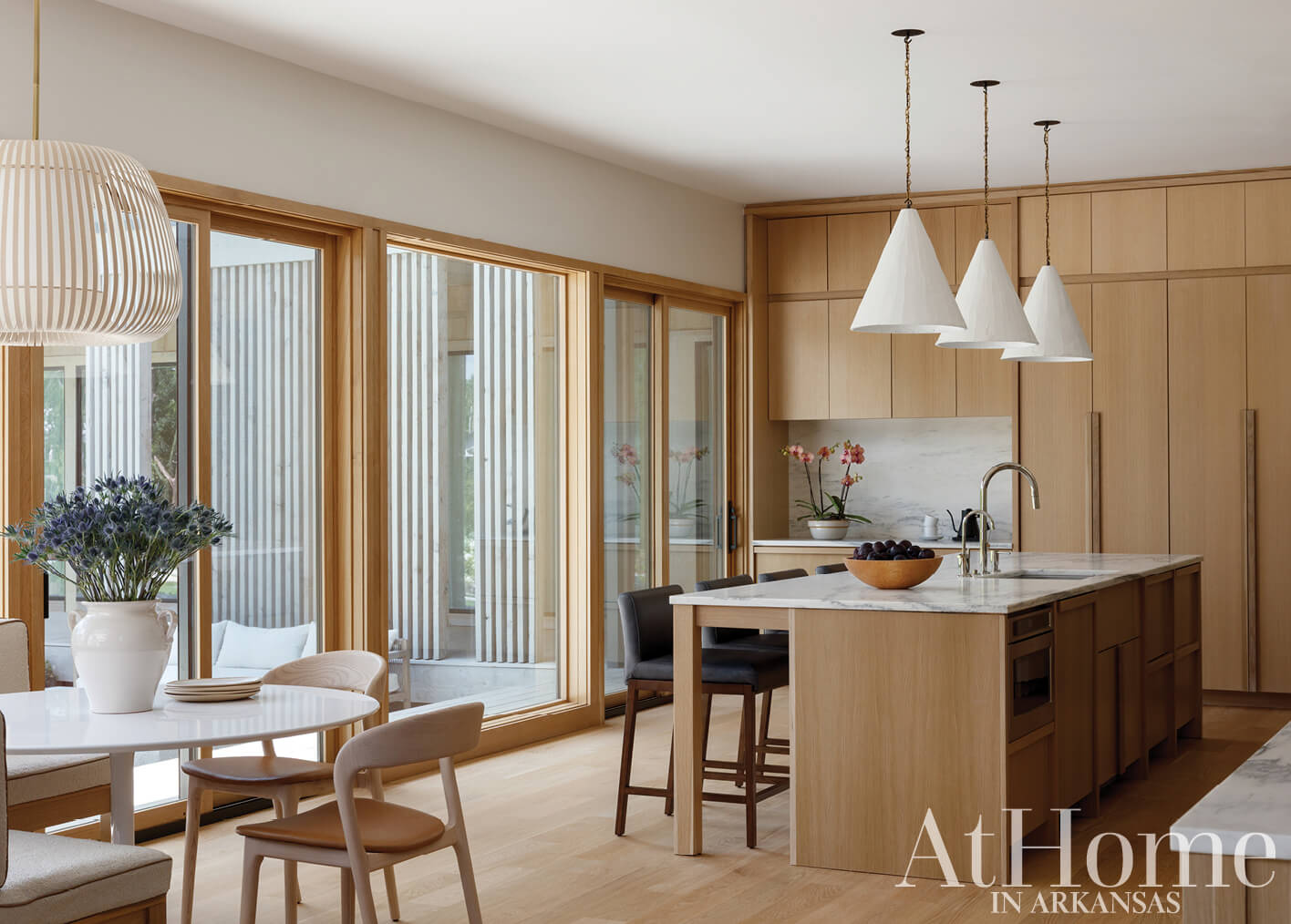 Wooden kitchen with pendant lights and marble island.