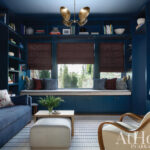 Deep blue room with built-in shelves, seating, and a gold chandelier.