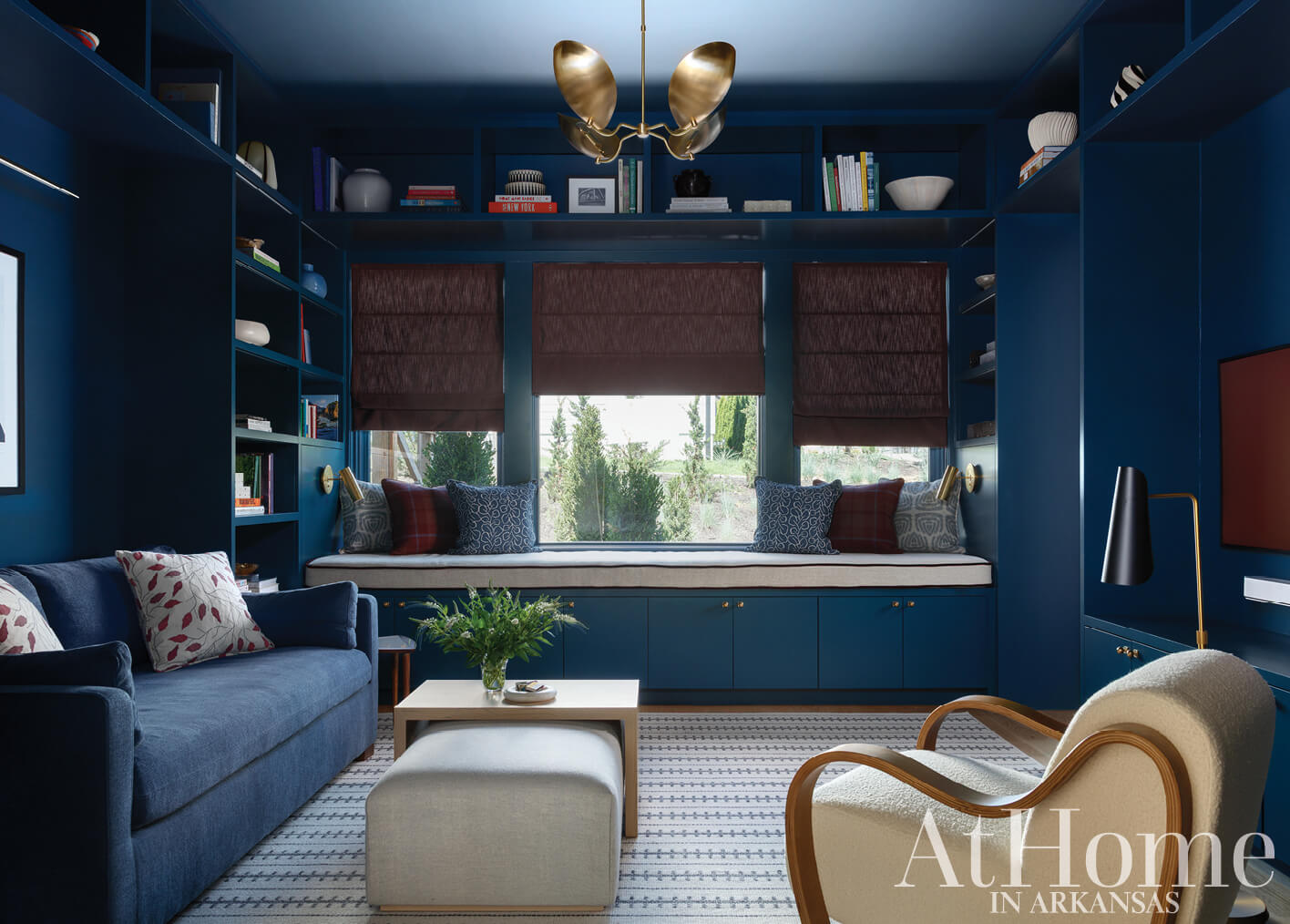 Deep blue room with built-in shelves, seating, and a gold chandelier.