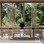 Outdoor dining table with chairs, pool, and wooden screens.