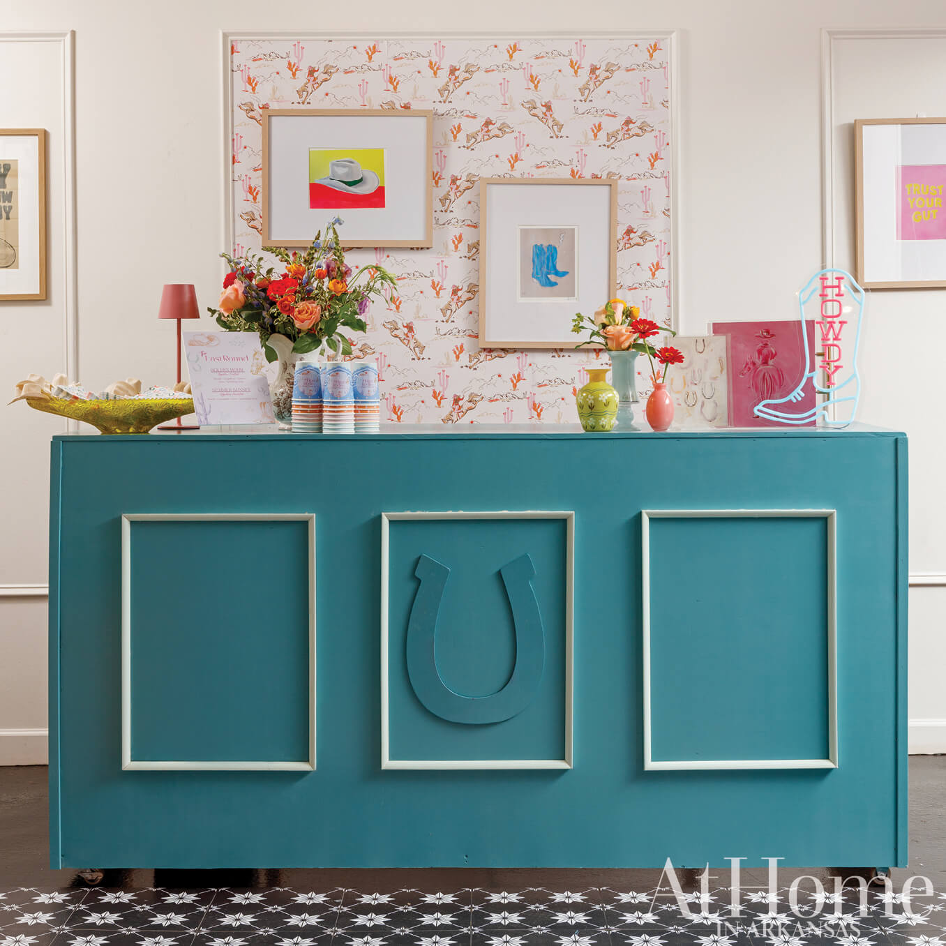 Turquoise console table with cactus wallpaper and floral arrangement.