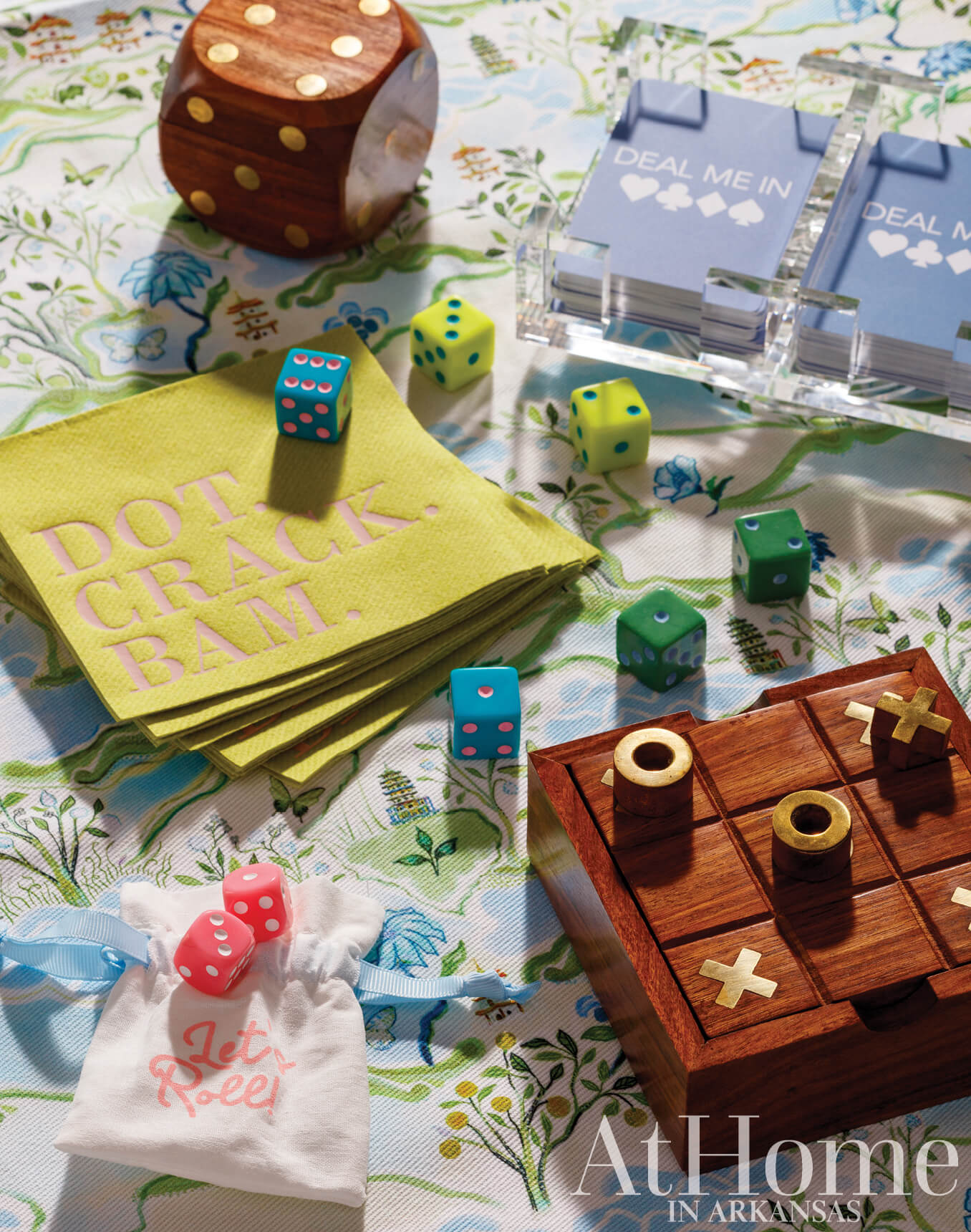 Dice, cards, and games on a patterned tablecloth.