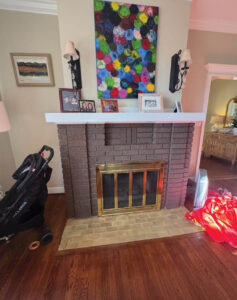 Brick fireplace with gold surround, artwork, and sconces.