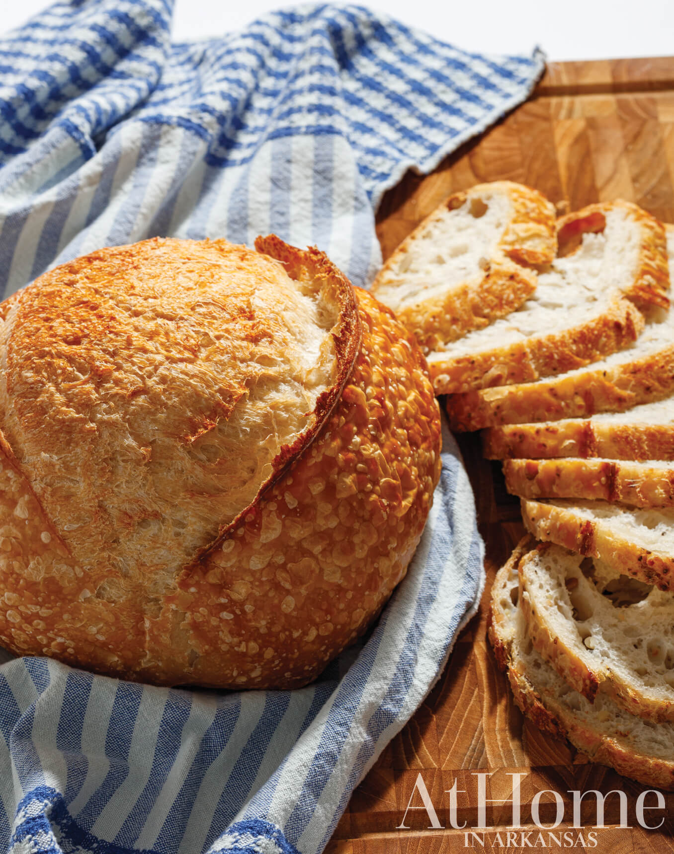 Sliced sourdough bread and boule on blue striped cloth.