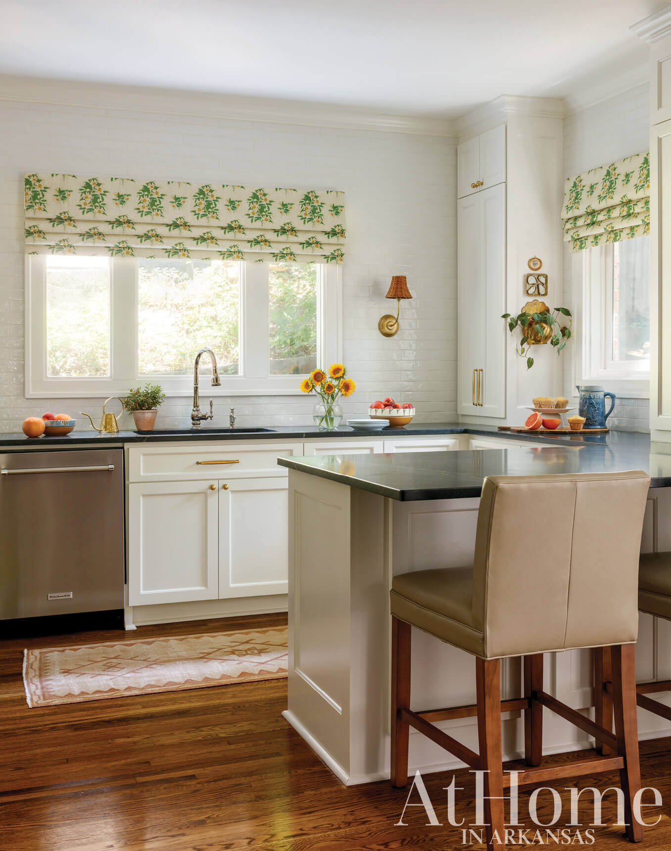 White kitchen with green patterned roman shade and black countertop.