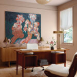 Wooden desk with a large abstract painting and a light fixture.