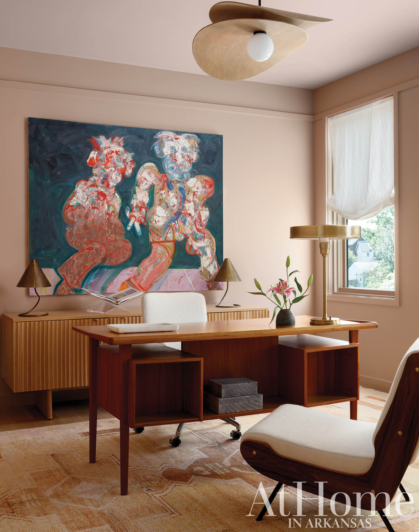 Wooden desk with a large abstract painting and a light fixture.