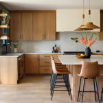 Wooden kitchen cabinets, marble countertop, and pendant lights.
