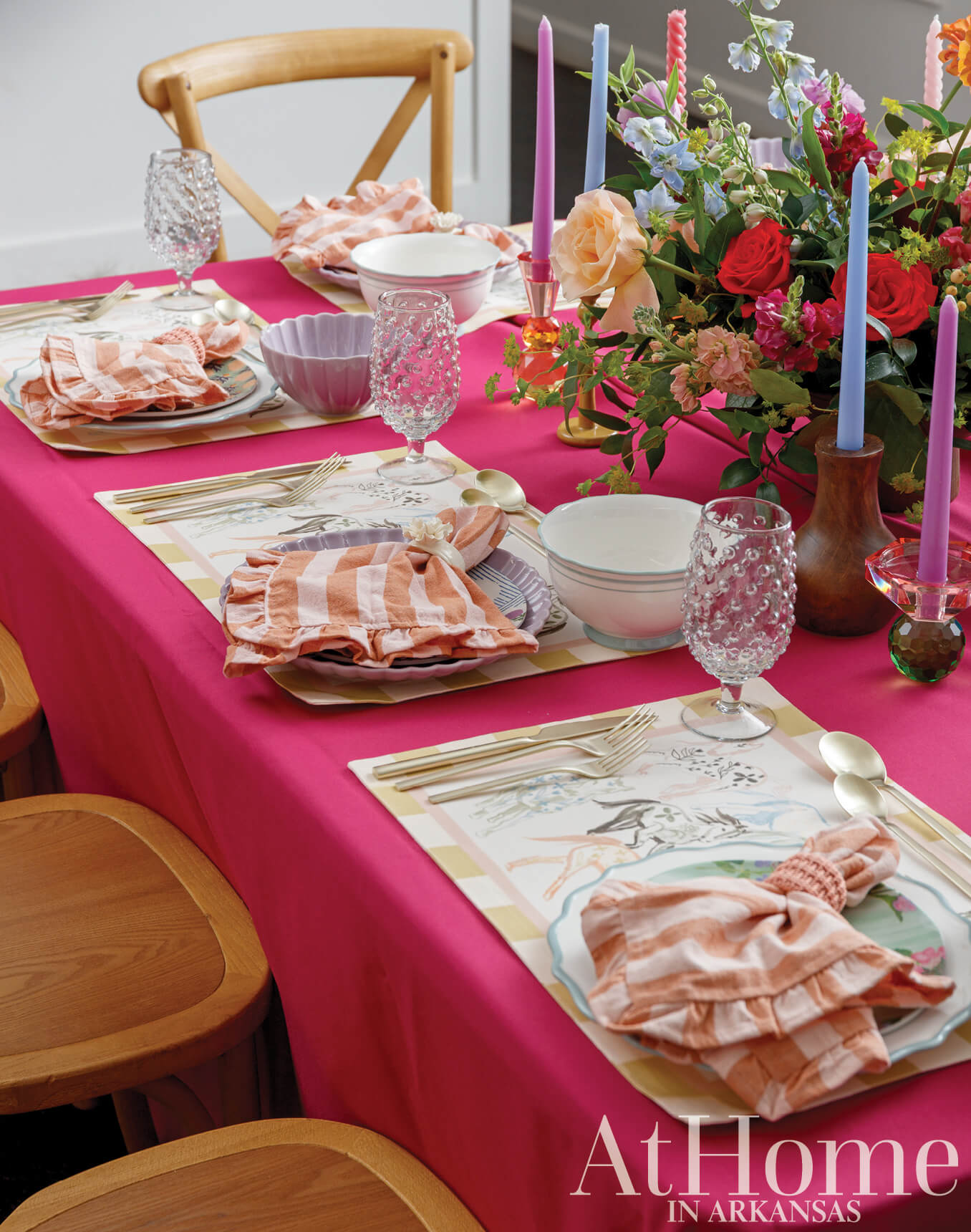 Pink and red table setting with floral centerpiece and placemats.
