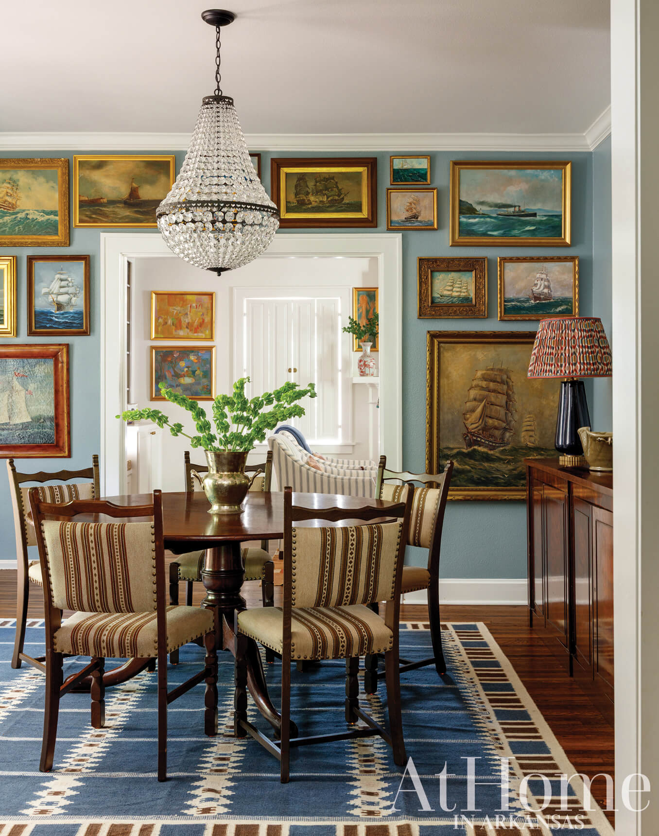 Formal dining room with a large chandelier and extensive artwork collection.