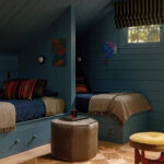 Blue-painted attic bedroom with two beds and storage.