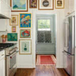 White kitchen with framed artwork and a patterned rug.
