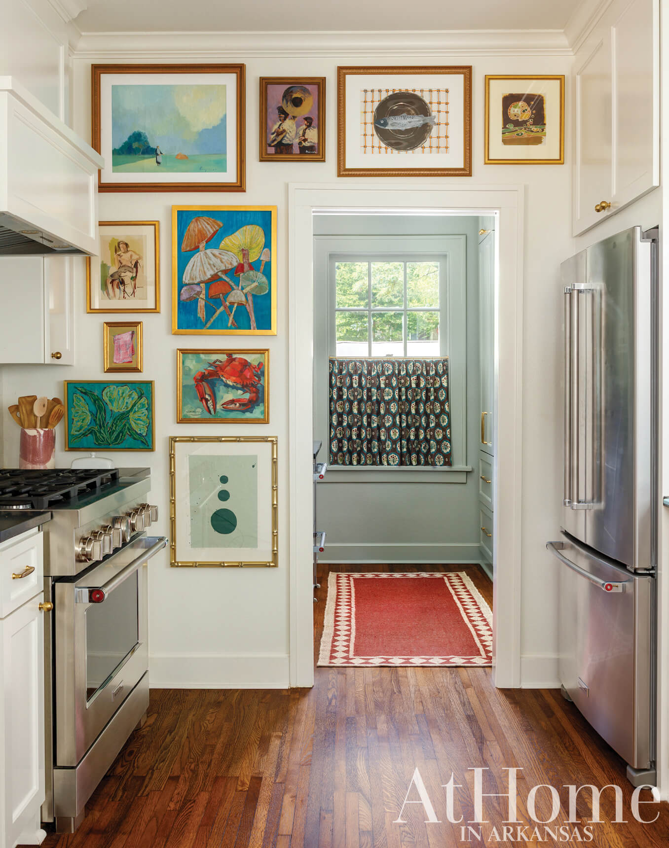 White kitchen with framed artwork and a patterned rug.