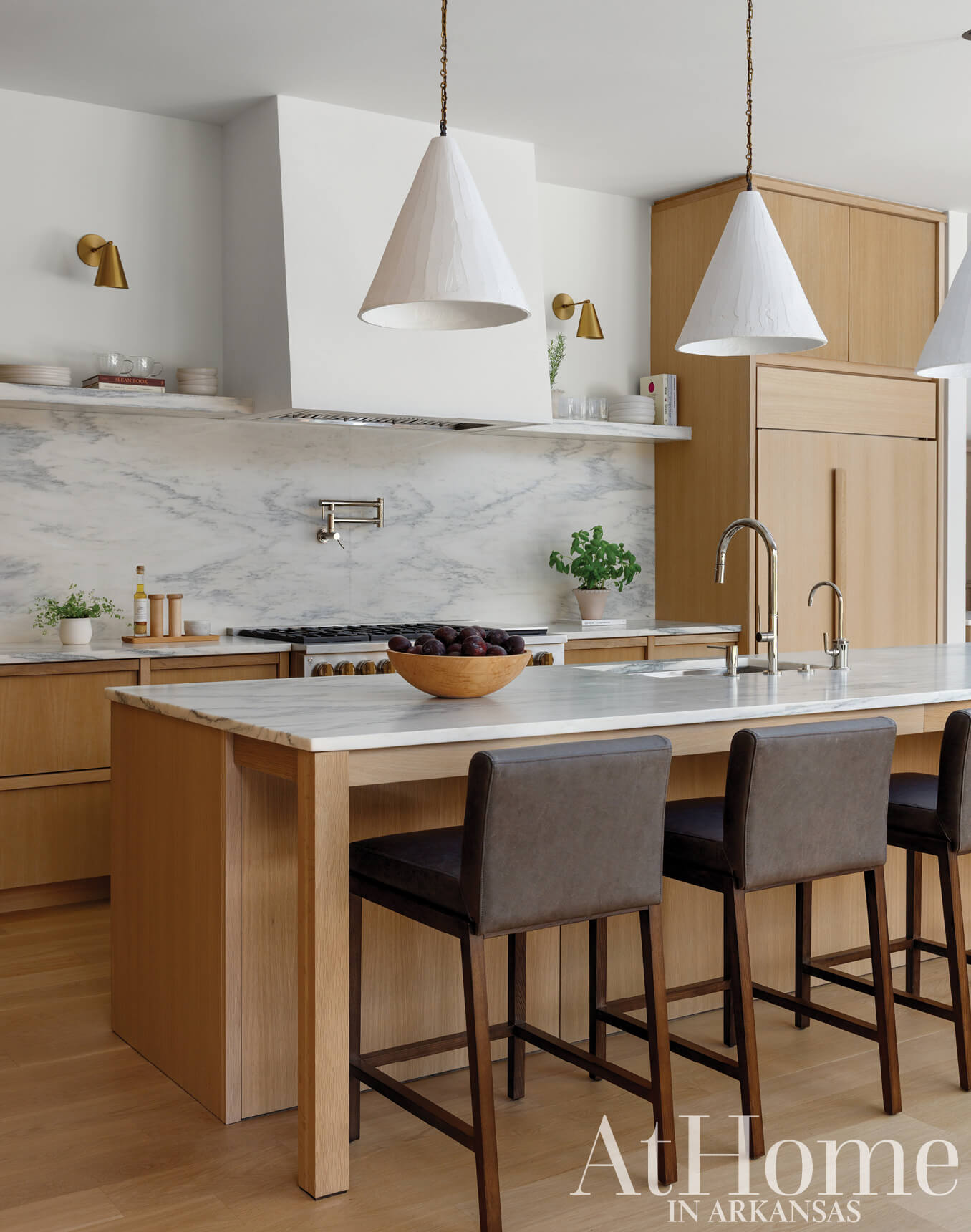 White marble kitchen island with wooden stools and pendant lights.