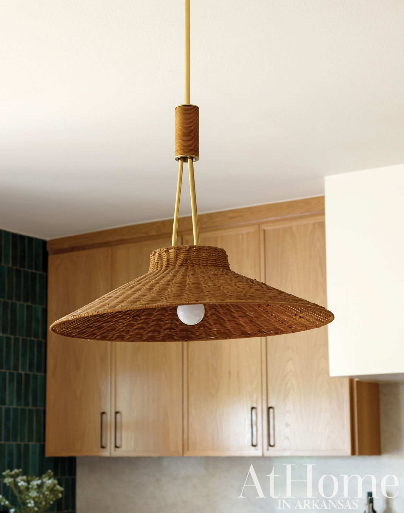Woven pendant light with a brass stem and bulb.