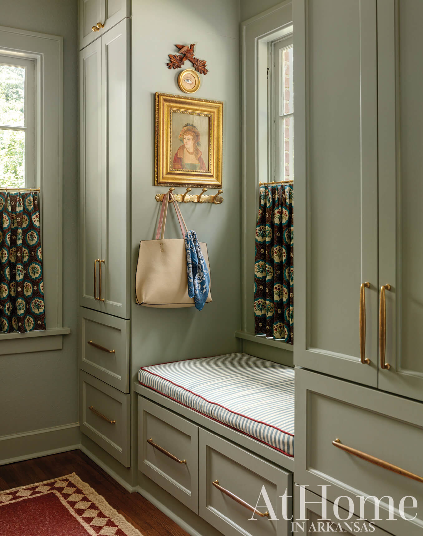 Gray built-in cabinets with a window seat and decorative artwork.