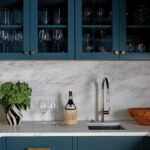 Dark teal cabinets with marble countertop and bar sink.