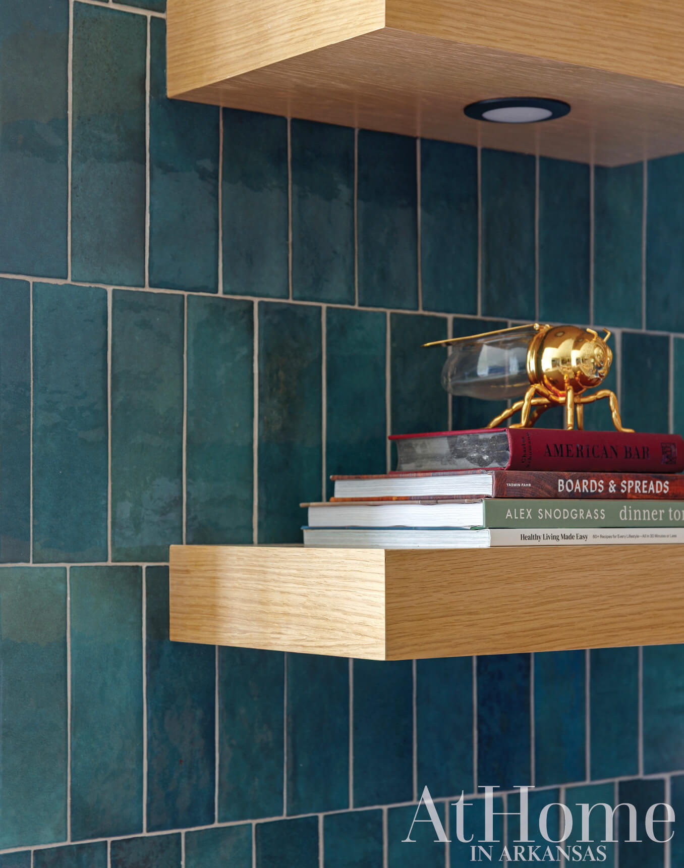 Wooden shelf with teal tile backsplash and books.