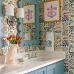 Powder room with teal wallpaper, mirror, and sink.