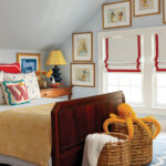 Blue and white bedroom with red window shades and artwork.