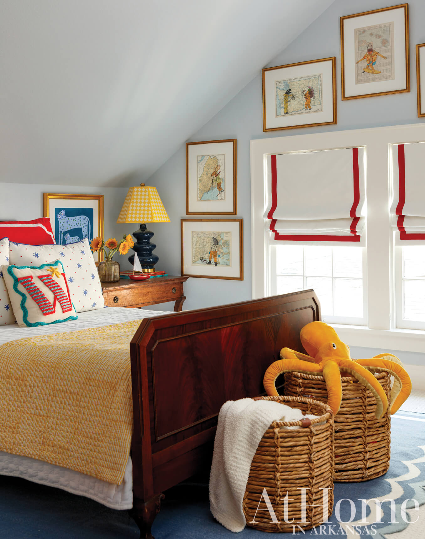 Blue and white bedroom with red window shades and artwork.