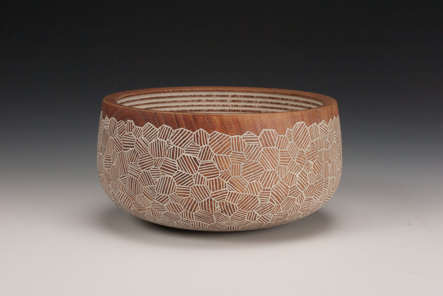 Wooden bowl with geometric white carving, brown finish.
