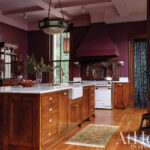 Dark wood kitchen with marble island and vintage appliances.