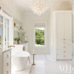 White bathroom with marble countertops and a large chandelier.