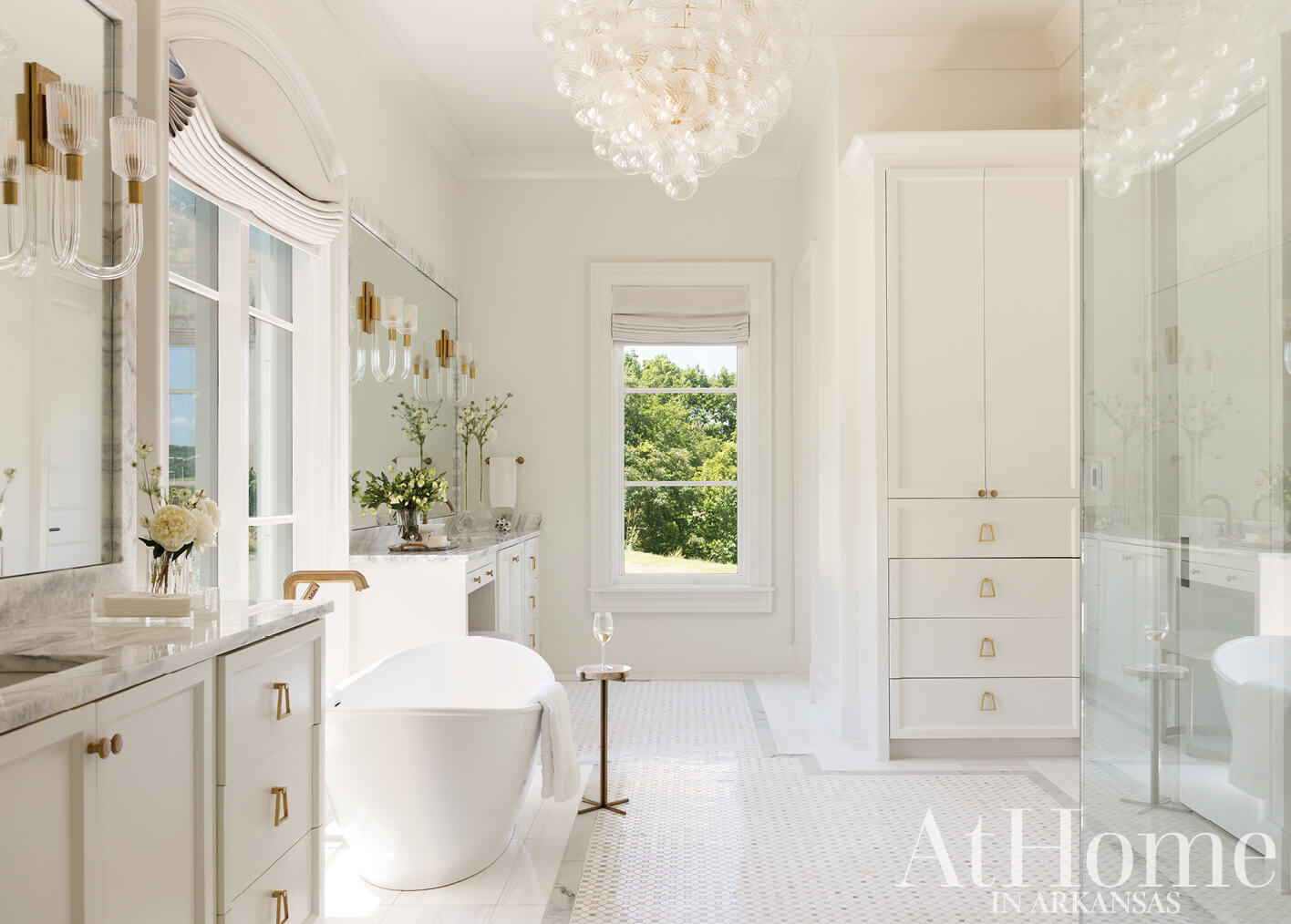 White bathroom with marble countertops and a large chandelier.
