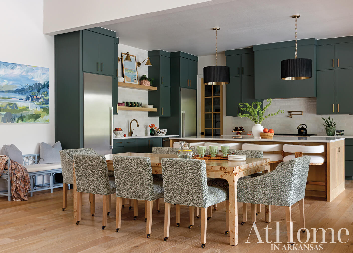 Dark green kitchen island with a stainless steel refrigerator and wooden dining table.