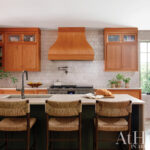Wooden kitchen cabinets with orange tile backsplash and island.