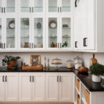 White cabinets with glass-fronted shelving and black countertops.