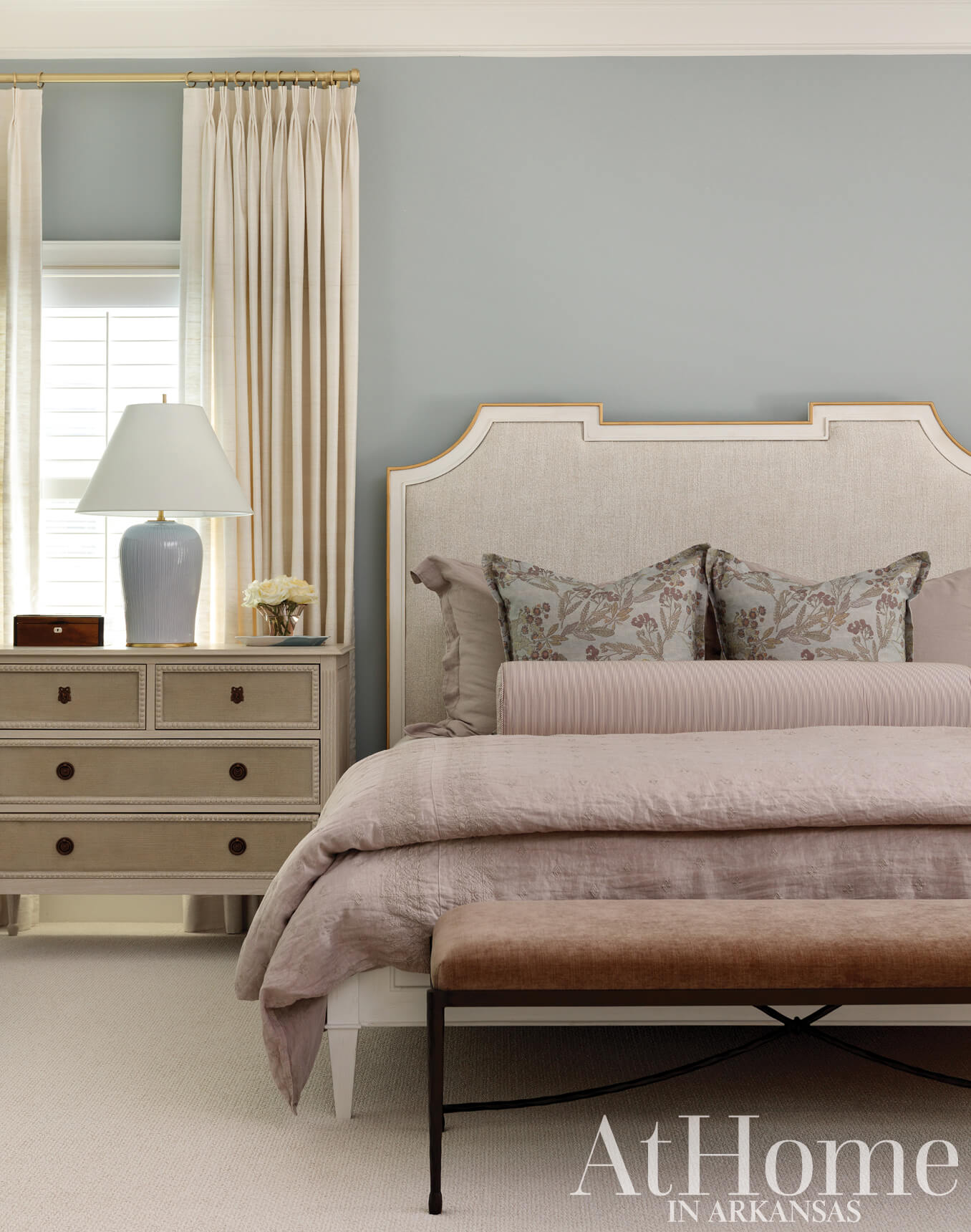 Master bedroom with a beige upholstered bed, pale blue walls, and a dresser.