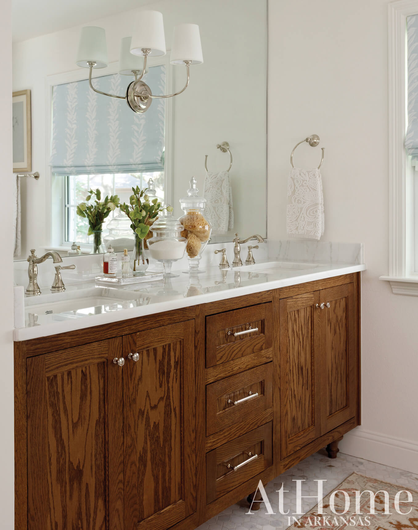 Wooden vanity with silver fixtures and mirror, window, and decorative accents.