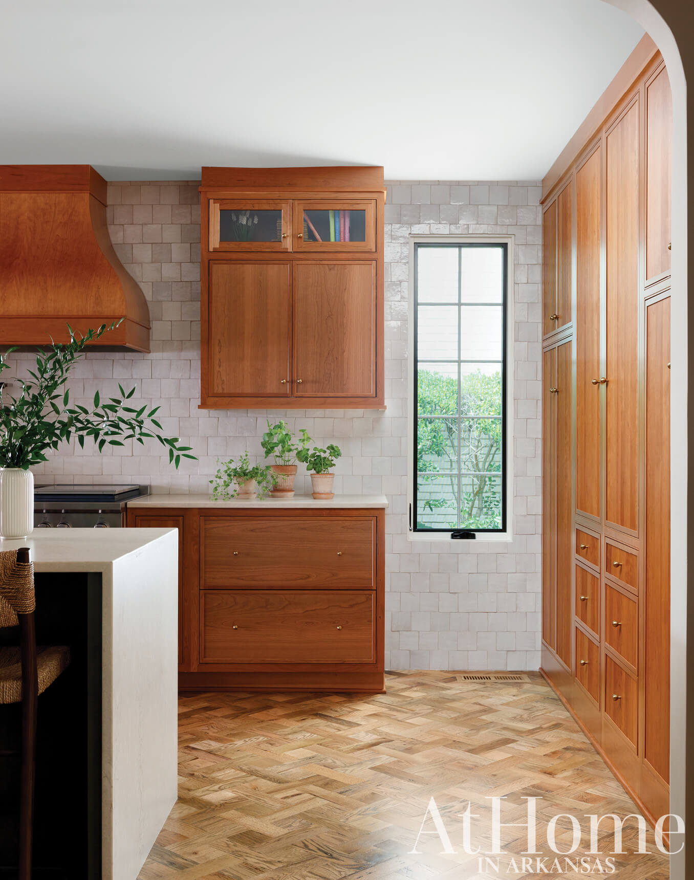 Warm wood kitchen with white subway tile and a window.