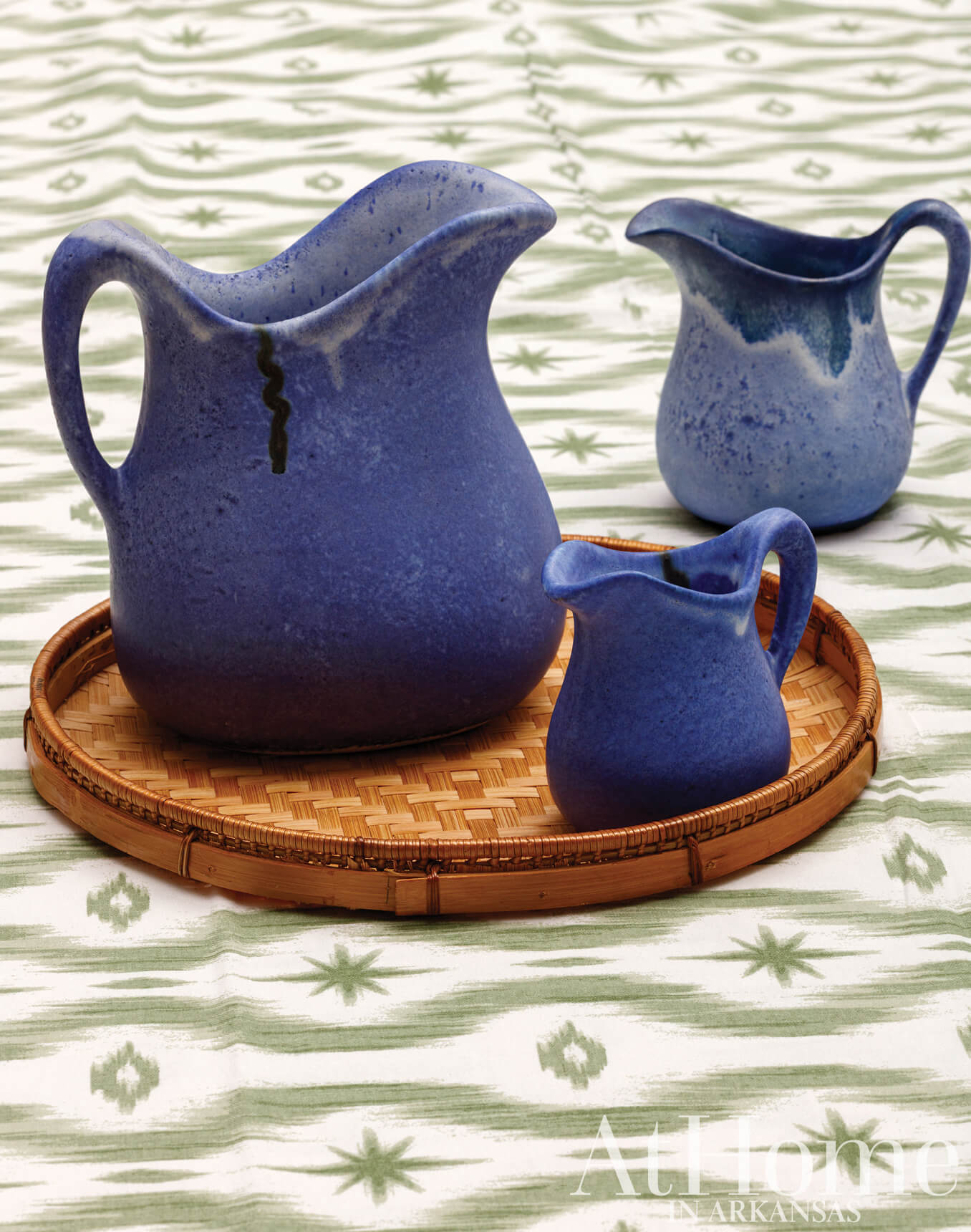 Blue ceramic pitchers on a woven tray.