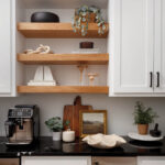 White cabinets with wooden shelves, coffee maker, and plants.