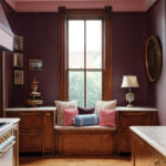 Dark wood-paneled alcove with window, built-in seating, and artwork.