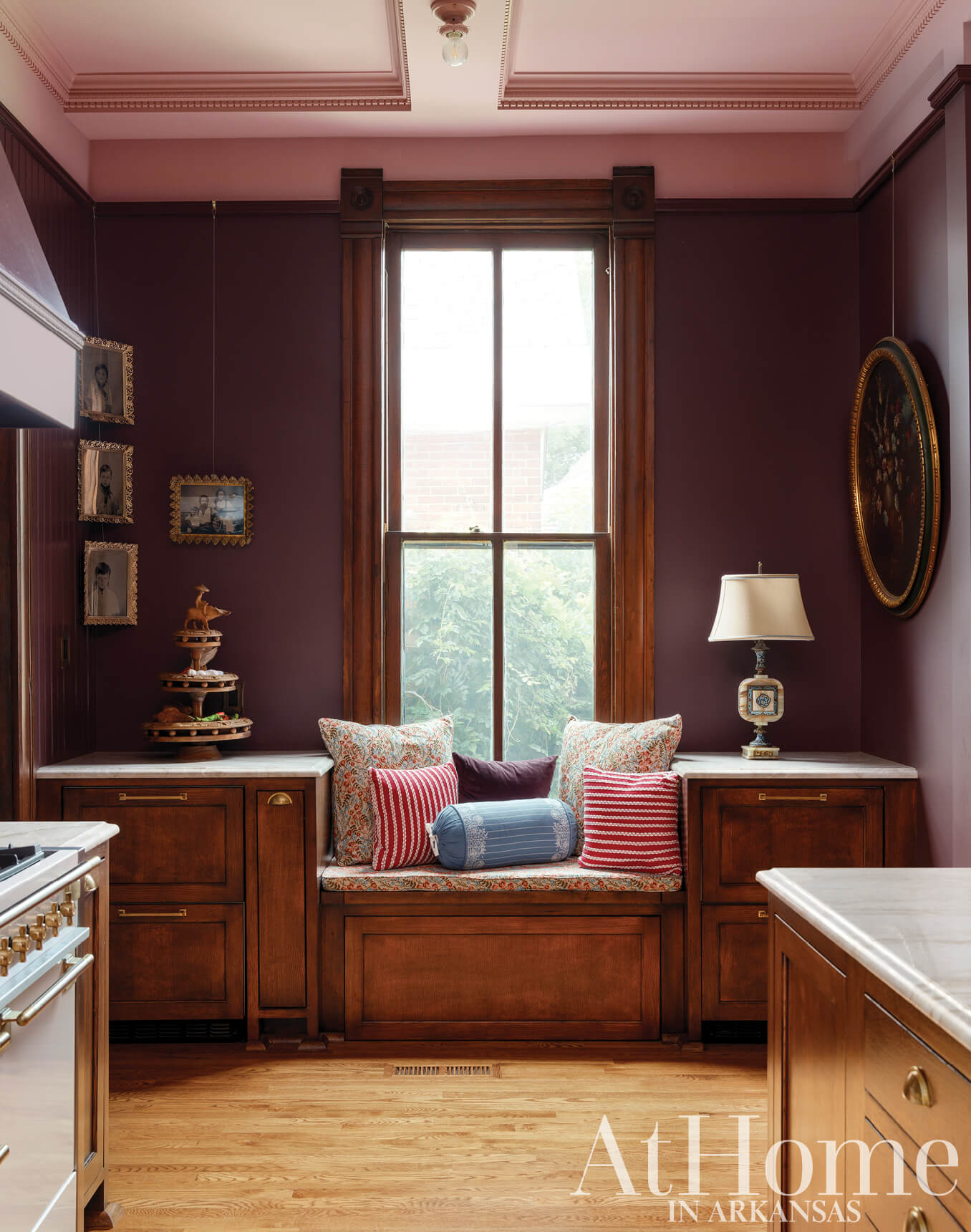 Dark wood-paneled alcove with window, built-in seating, and artwork.