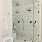 White marble shower with brass fixtures and glass enclosure.