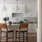 White kitchen with marble tile backsplash and wood cabinetry.