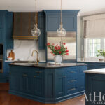 Dark teal kitchen island with marble countertop and brass fixtures.