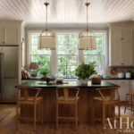 White kitchen with island, pendant lights, and wood cabinetry.