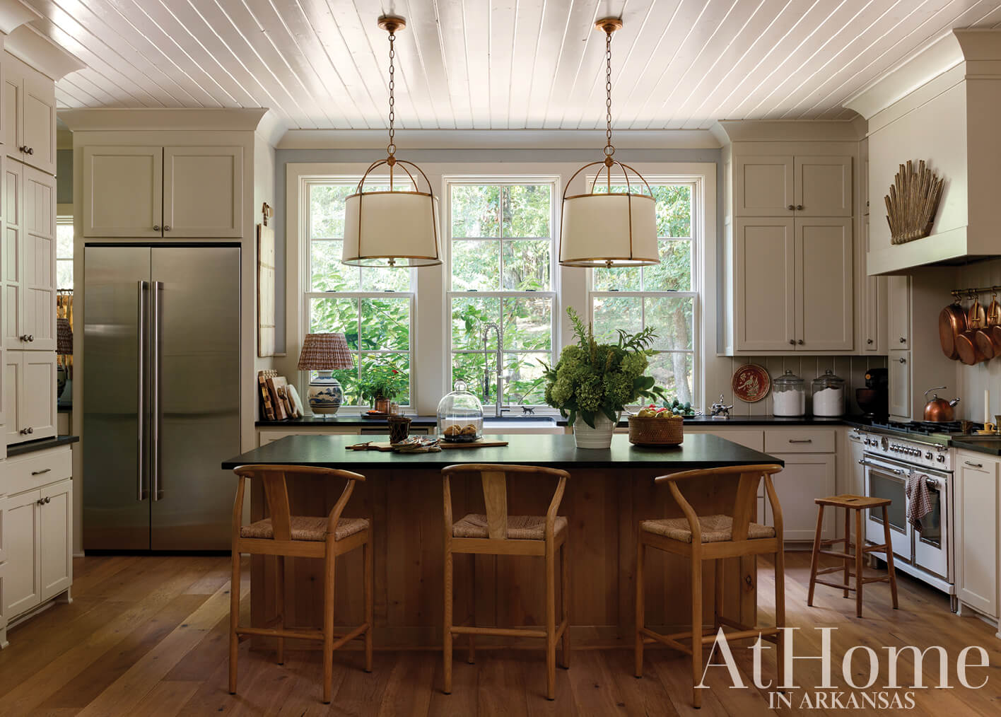 White kitchen with island, pendant lights, and wood cabinetry.